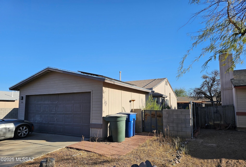 view of side of property with a garage, fence, and a gate