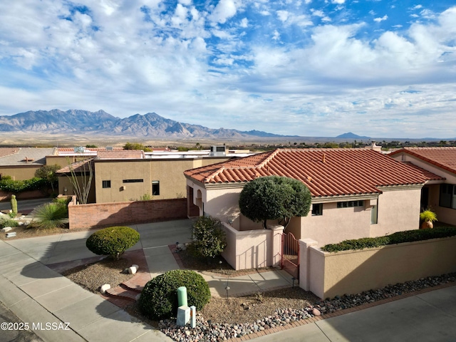 view of front of property featuring a fenced front yard, a mountain view, a tiled roof, a gate, and stucco siding