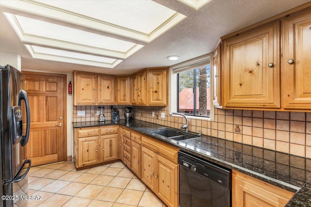 kitchen with light tile patterned floors, decorative backsplash, dark stone countertops, black appliances, and a sink