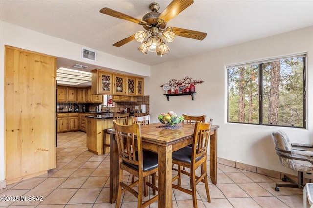 dining space with light tile patterned floors, baseboards, visible vents, and a ceiling fan