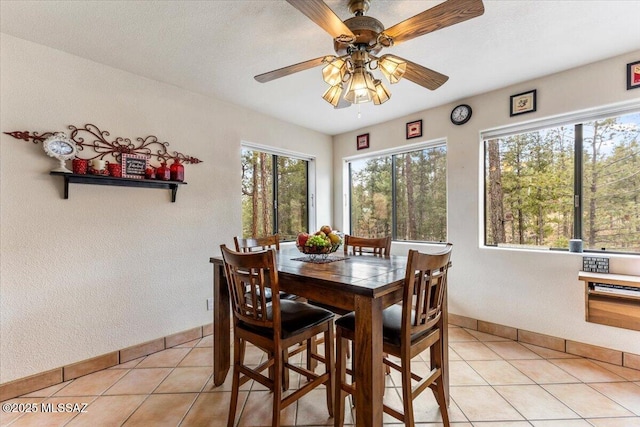 dining space featuring light tile patterned floors, ceiling fan, and baseboards