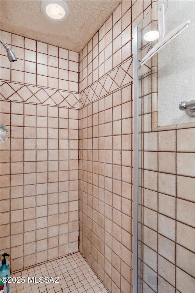 bathroom with a textured ceiling and tiled shower