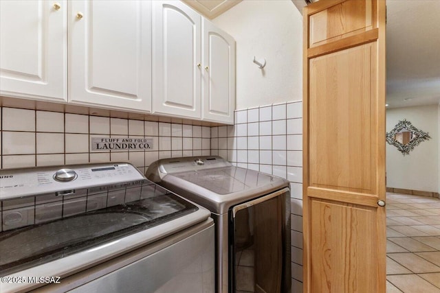 clothes washing area with light tile patterned floors, cabinet space, and separate washer and dryer