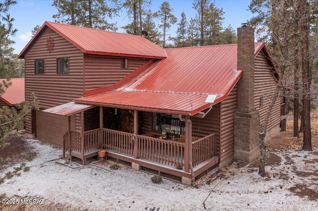 exterior space with a porch, metal roof, and a chimney