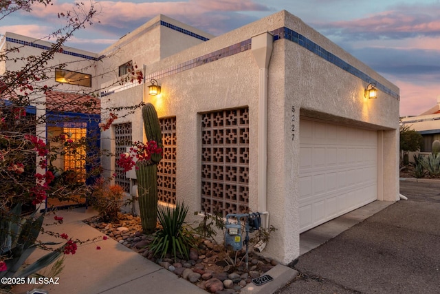 view of side of home with a garage and stucco siding