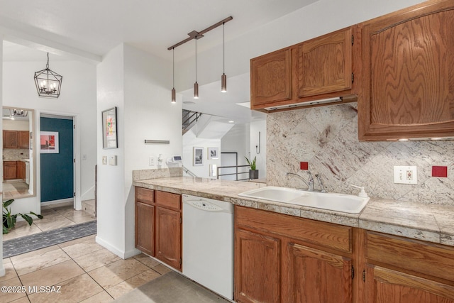 kitchen with white dishwasher, a sink, backsplash, brown cabinets, and pendant lighting