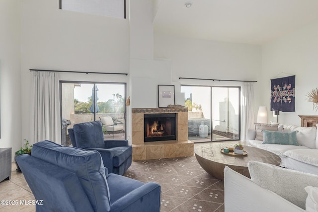 living room featuring a wealth of natural light, a fireplace, a high ceiling, and tile patterned floors