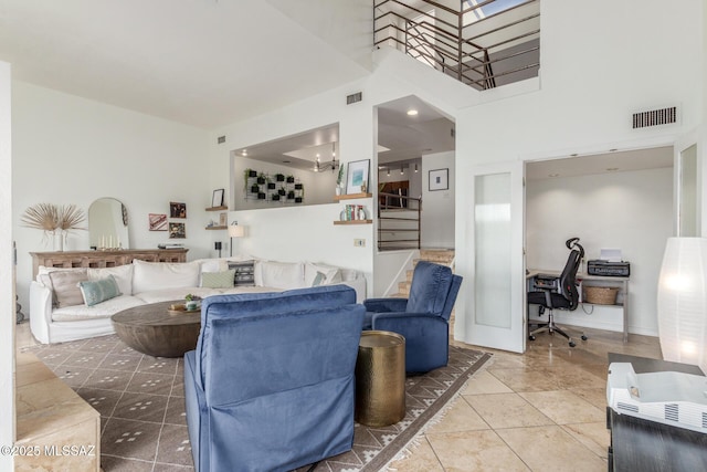 tiled living area with a towering ceiling, baseboards, stairs, and visible vents