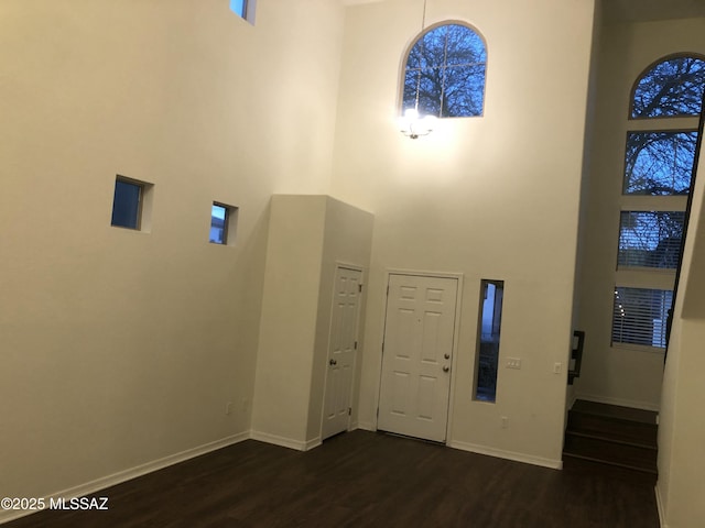 entryway featuring baseboards, dark wood finished floors, and a high ceiling