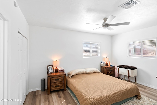 bedroom featuring light wood-style floors, baseboards, visible vents, and a closet