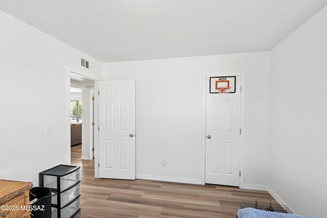 bedroom with light wood-style floors, visible vents, and baseboards