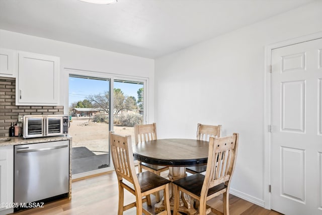 dining area featuring baseboards, light wood-style flooring, and a toaster