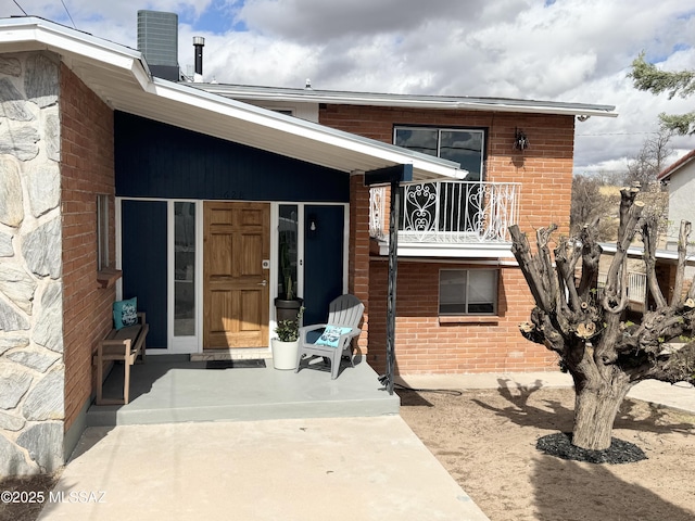 rear view of property with a balcony and brick siding