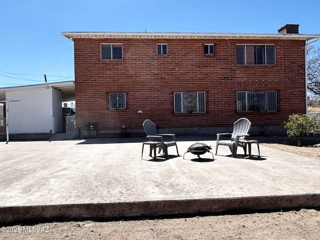 back of house with a patio area, a chimney, and an outdoor fire pit