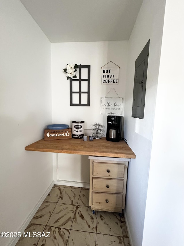 unfurnished office featuring electric panel, baseboards, and marble finish floor