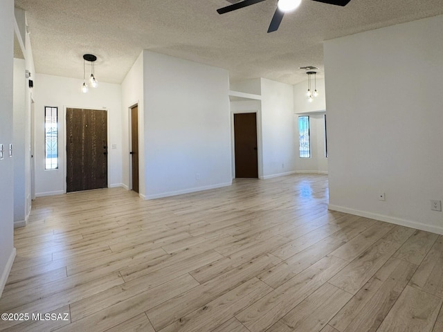 interior space featuring a ceiling fan, baseboards, light wood-style flooring, and a textured ceiling