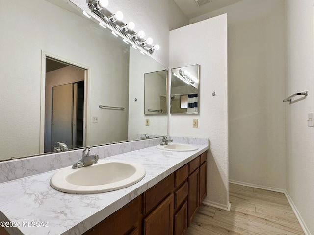 bathroom featuring double vanity, visible vents, a sink, and wood finished floors
