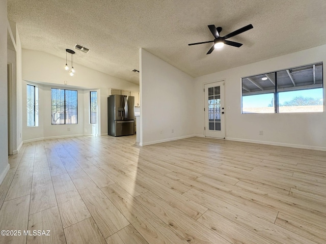 unfurnished living room featuring lofted ceiling, light wood-style flooring, plenty of natural light, visible vents, and ceiling fan
