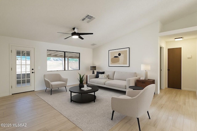 living area with lofted ceiling, a ceiling fan, visible vents, and light wood-type flooring