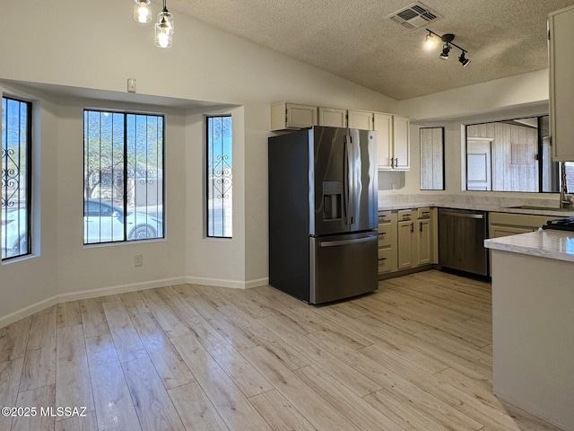 kitchen featuring vaulted ceiling, a sink, dishwasher, stainless steel refrigerator with ice dispenser, and visible vents