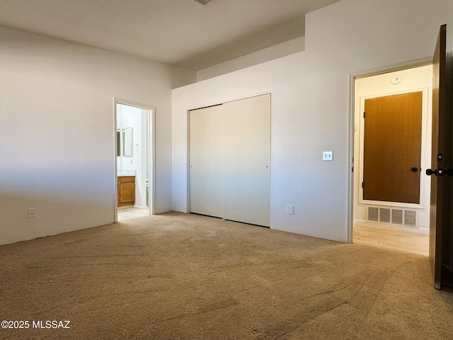 unfurnished bedroom with visible vents, a closet, ensuite bath, and carpet flooring