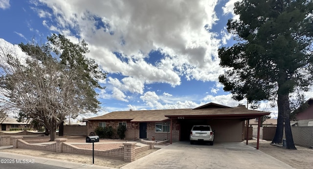 ranch-style home featuring driveway, fence, and brick siding