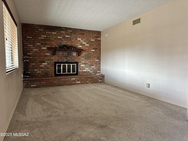 unfurnished living room featuring visible vents, a fireplace, a textured ceiling, and carpet flooring