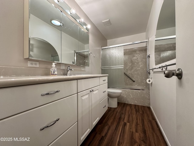 bathroom featuring enclosed tub / shower combo, toilet, wood finished floors, visible vents, and vanity