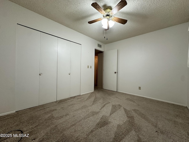 unfurnished bedroom featuring a textured ceiling, carpet floors, visible vents, a ceiling fan, and a closet