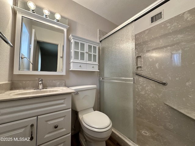 bathroom featuring visible vents, toilet, a shower stall, and vanity