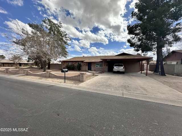 single story home featuring a carport, concrete driveway, brick siding, and fence