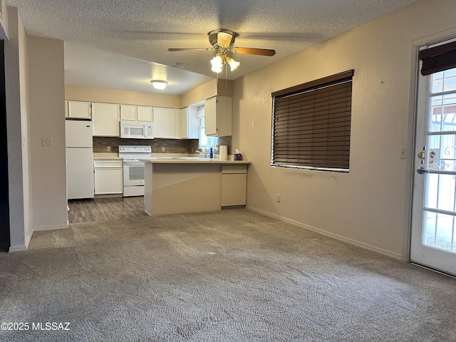 kitchen featuring white appliances, a peninsula, dark colored carpet, a textured ceiling, and light countertops