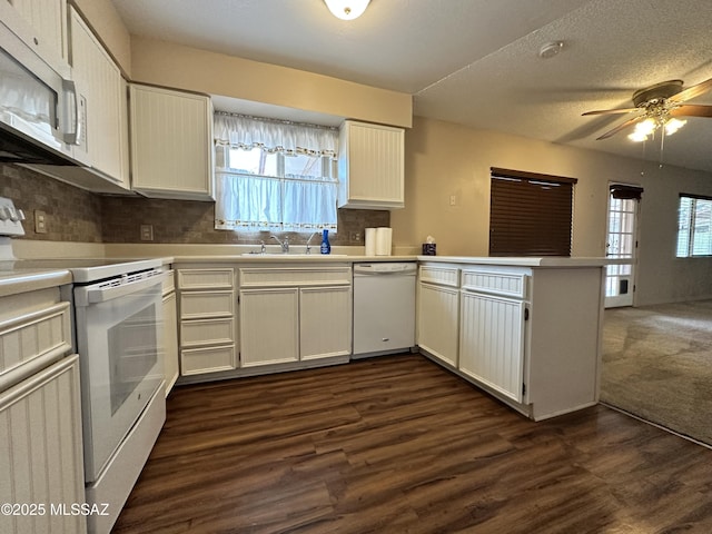 kitchen with white appliances, decorative backsplash, dark wood-style floors, a peninsula, and a sink