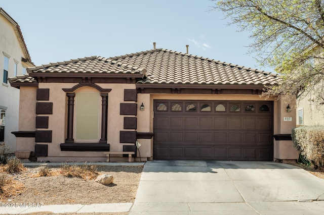 view of front of property featuring a garage, driveway, a tiled roof, and stucco siding