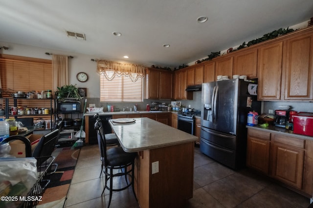 kitchen with brown cabinetry, tile patterned flooring, visible vents, and stainless steel appliances