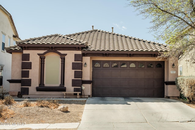 view of front of home with an attached garage, driveway, a tiled roof, and stucco siding