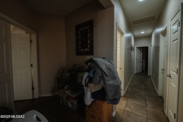 hallway with baseboards, attic access, and tile patterned floors