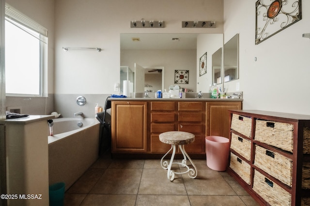 full bath featuring double vanity, a garden tub, a sink, and tile patterned floors