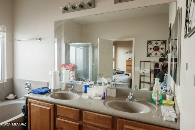 bathroom with double vanity, a stall shower, a sink, and ensuite bath