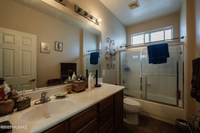 bathroom with toilet, shower / bath combination with glass door, vanity, visible vents, and tile patterned floors