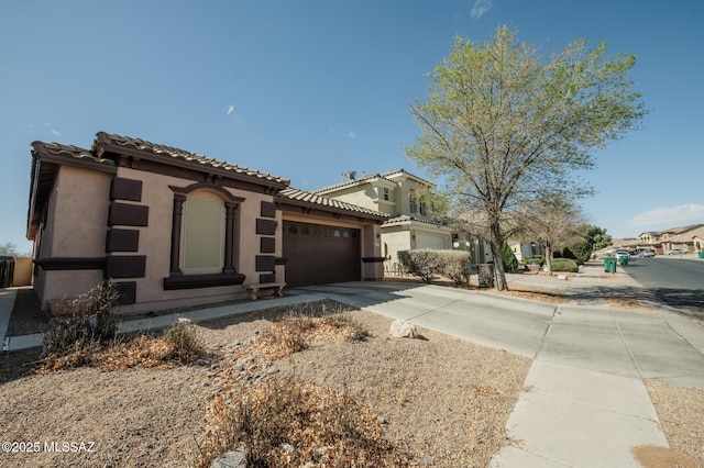 mediterranean / spanish-style home featuring concrete driveway, a tiled roof, an attached garage, and stucco siding