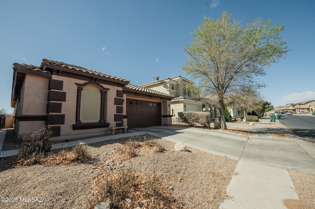 mediterranean / spanish-style house featuring a garage, a tiled roof, concrete driveway, and stucco siding
