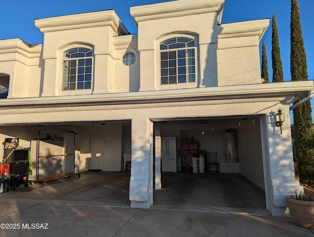 view of front of home with water heater, stucco siding, and an attached garage