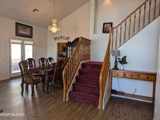 dining space with visible vents, high vaulted ceiling, wood finished floors, an inviting chandelier, and stairs