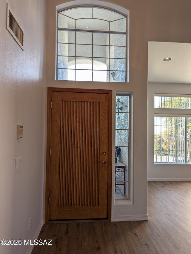 foyer entrance with visible vents, baseboards, and wood finished floors