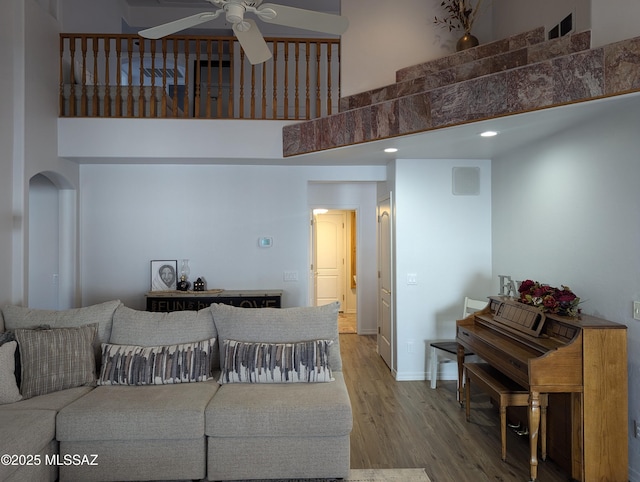 living room with a high ceiling, wood finished floors, baseboards, and ceiling fan