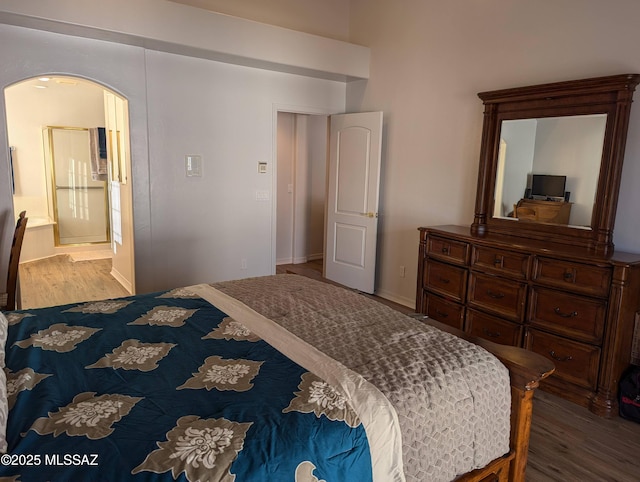 bedroom with arched walkways and wood finished floors