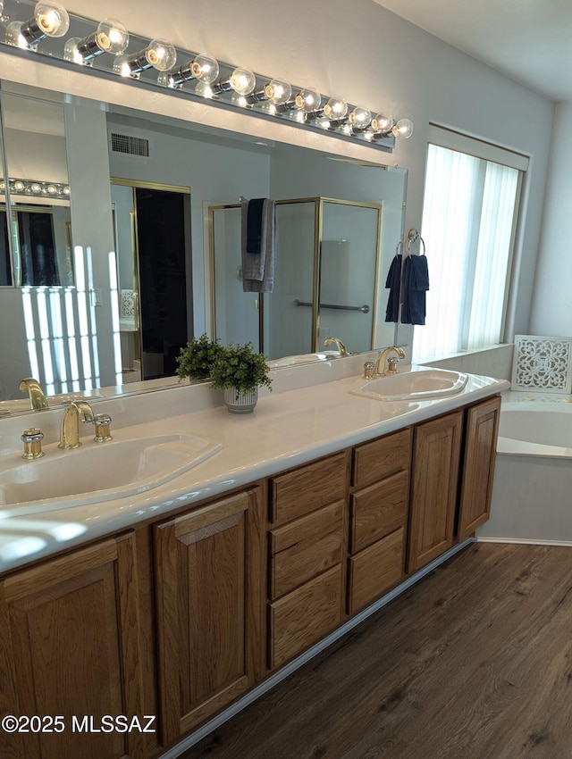 full bath with visible vents, a shower stall, wood finished floors, and a sink