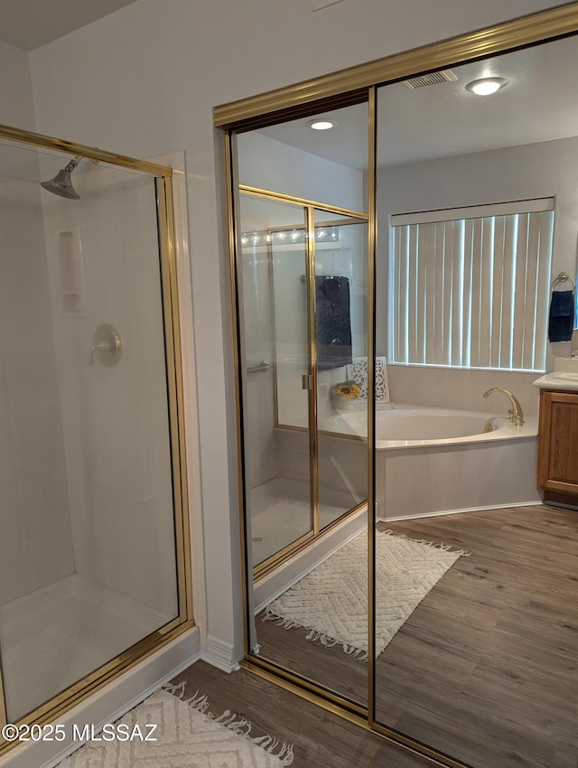 bathroom featuring a stall shower, a garden tub, and wood finished floors