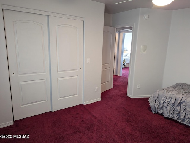 bedroom featuring a closet, baseboards, and dark carpet